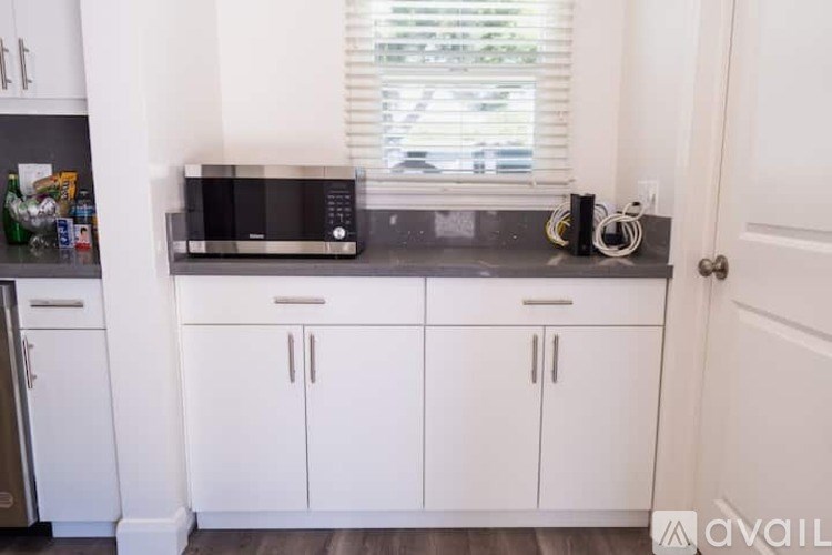 A kitchen with white cabinets and a black microwave.