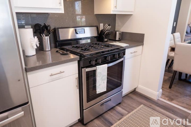 A modern kitchen with a stainless steel refrigerator, a black stove top, and white cabinets.