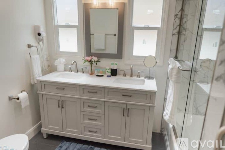A white bathroom with a sink, mirror, and toilet.