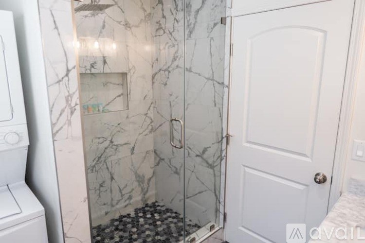 A bathroom with a marble wall and a white door.