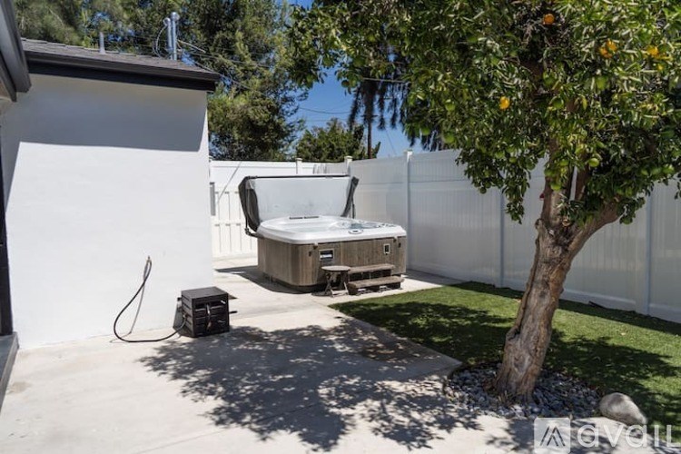 A hot tub is placed on a patio next to a tree.