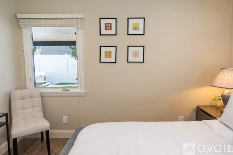 A bedroom with a bed, chair, and pictures on the wall.