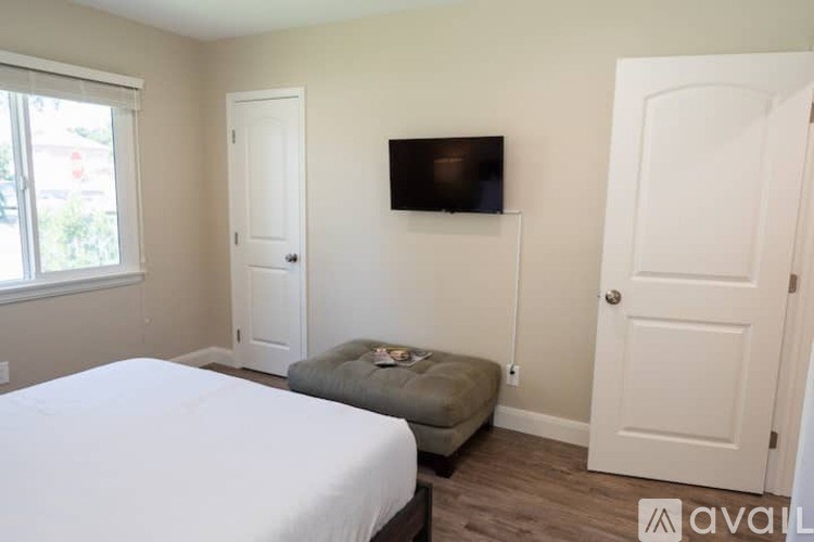 A bedroom with a bed, a couch, and a TV mounted on the wall.