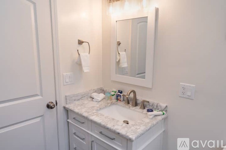 A bathroom with a marble countertop and a large mirror above it.