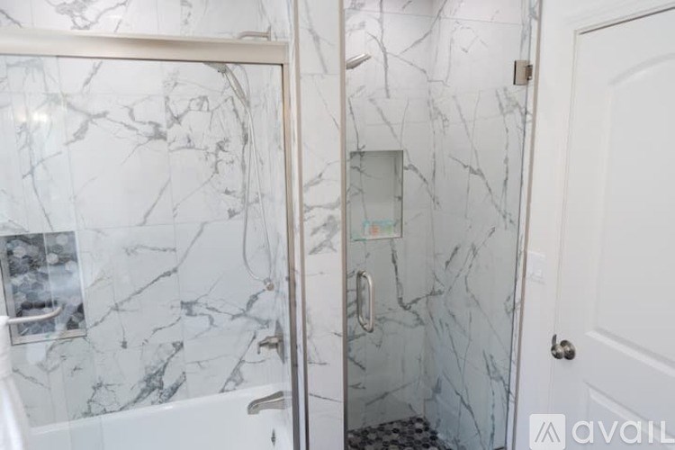 A bathroom with marble tiles and a glass shower door.