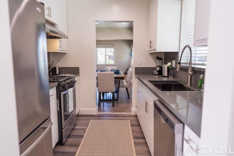 A kitchen with a refrigerator, oven, and sink.