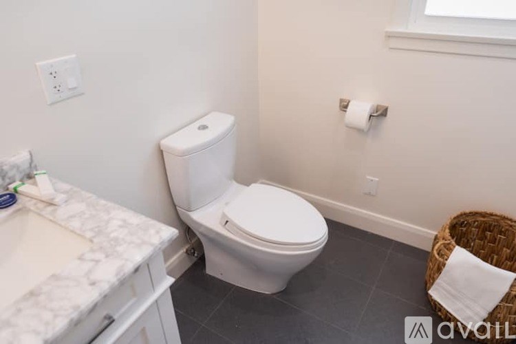 A white toilet in a bathroom with a marble countertop and a basket.