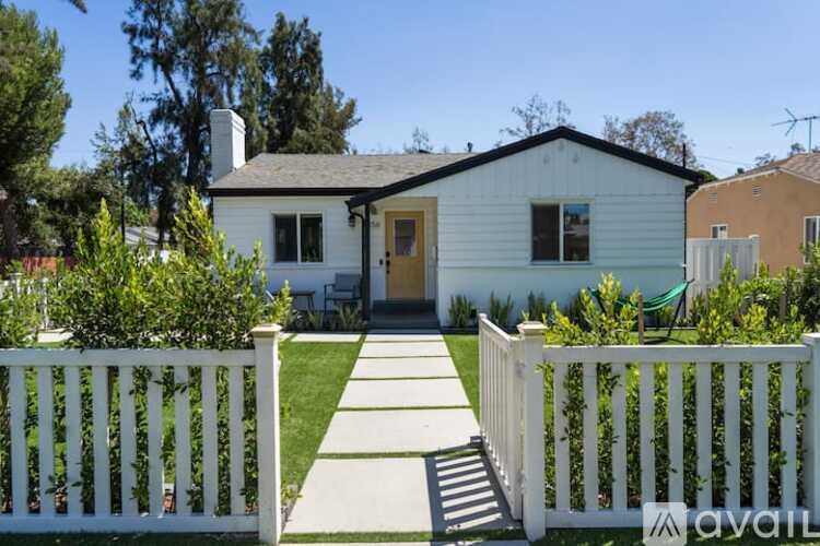 A white house with a white picket fence in front.
