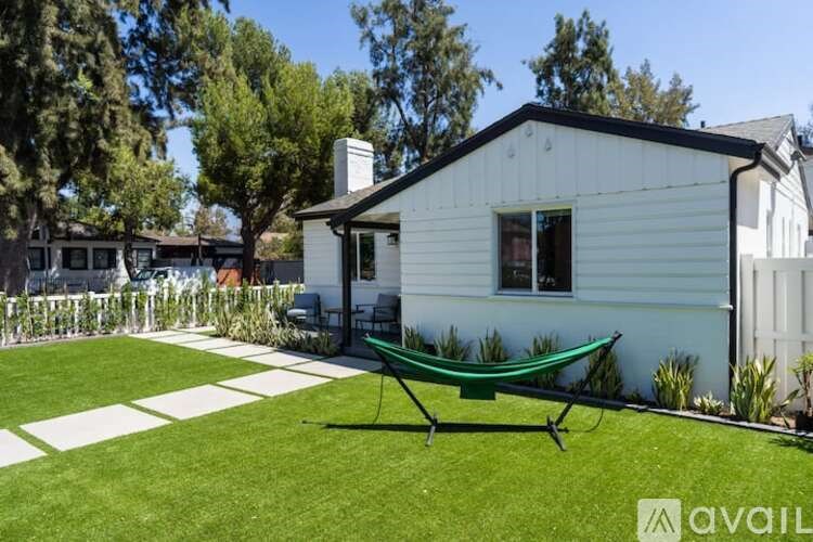 A white house with a green hammock in the yard.