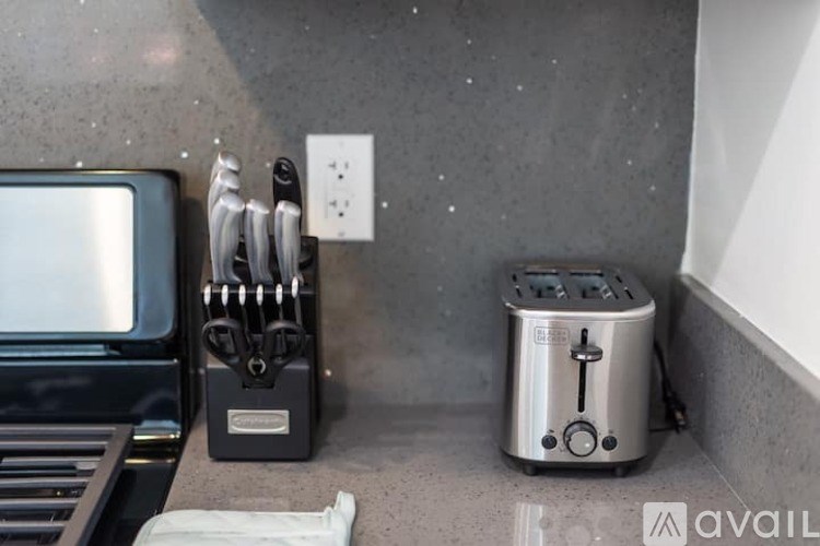 A toaster is on a counter next to a knife block.