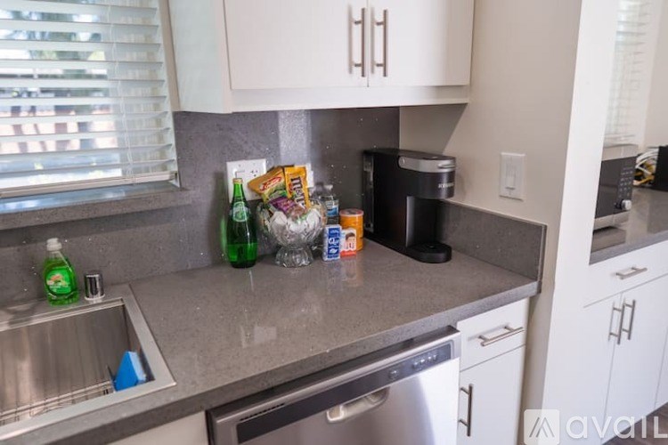 A kitchen with a sink, dishwasher, and a coffee maker.