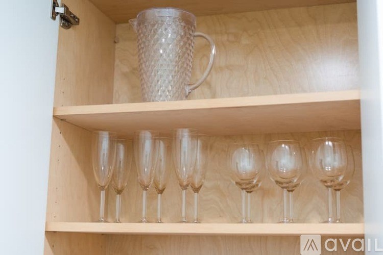 A set of wine glasses are lined up on a shelf.