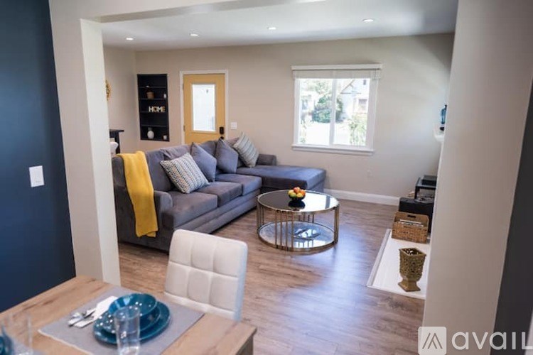 A modern living room with a grey couch and a yellow throw.