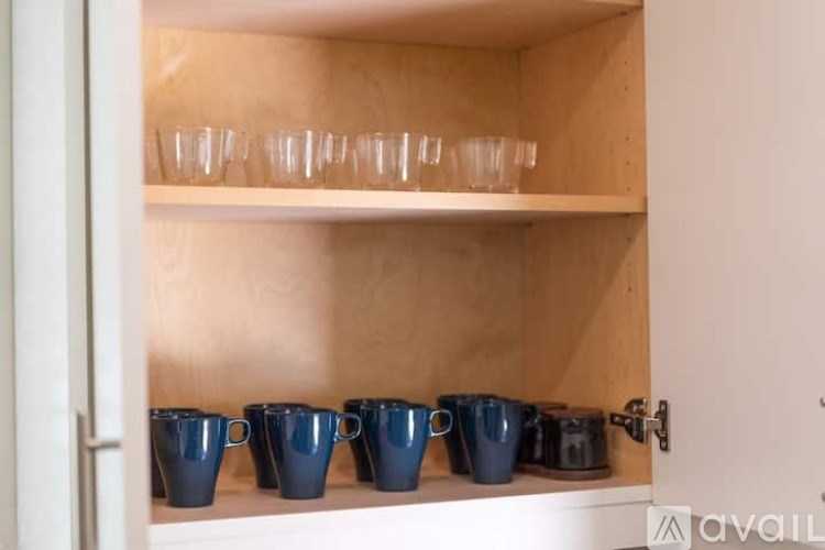 A kitchen cabinet with blue cups and glasses on the shelf.