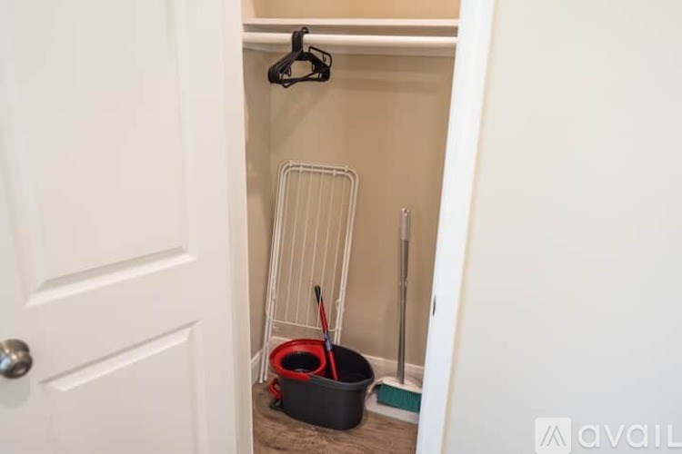 A black mop is leaning against a white wall in a small room.