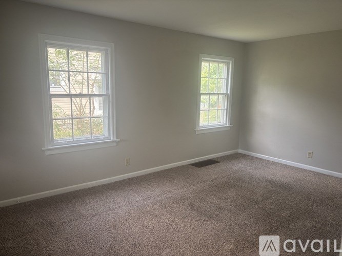 A room with two windows and carpeted floor.