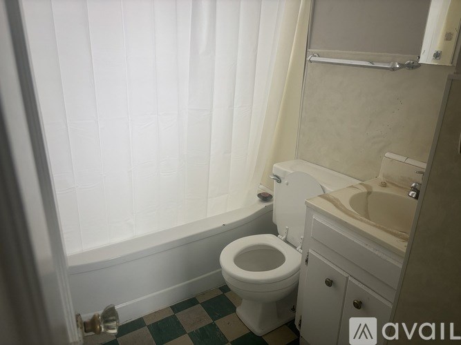 A white toilet in a bathroom with a green and white checkered floor.