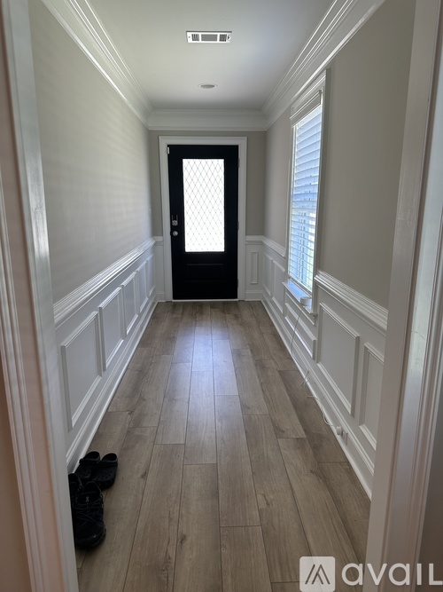 A hallway with a black door and a pair of shoes on the floor.