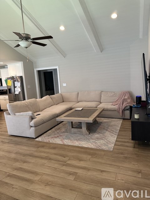 A living room with a beige couch and a ceiling fan.