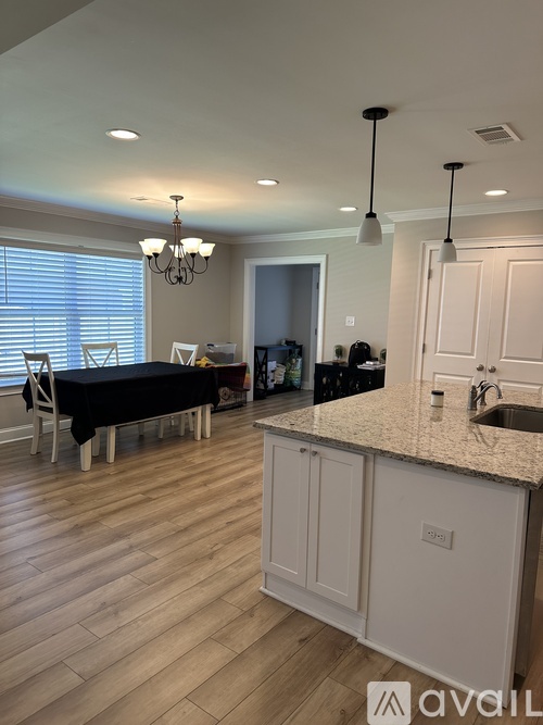 A kitchen with a table and chairs in the foreground and a sink in the background.