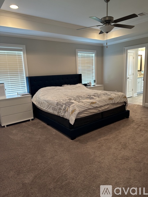 A bedroom with a bed, dresser, and ceiling fan.