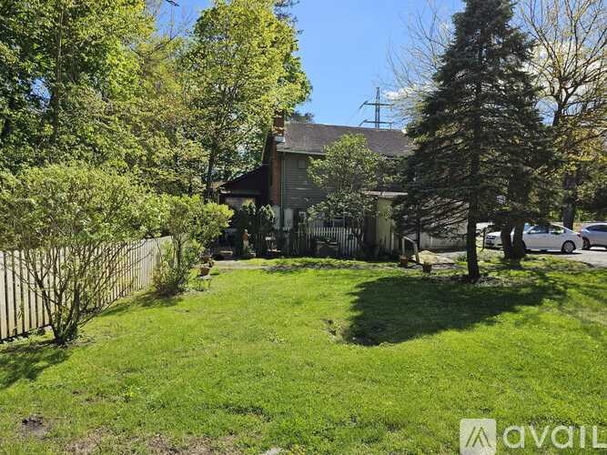 A backyard with a fence, trees, and a house in the background.