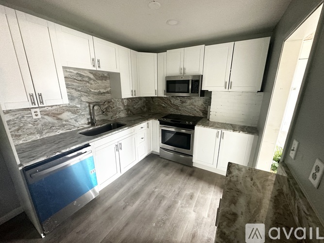 A kitchen with white cabinets and a marble backsplash.
