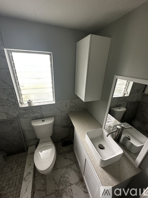 A bathroom with a toilet, sink, and mirror.
