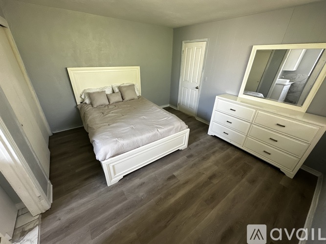 A bedroom with a bed, dresser, and mirror.