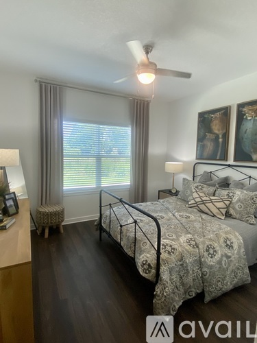 A bedroom with a bed, nightstand, and window with blinds.