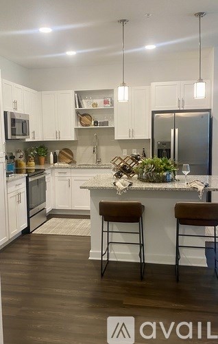A kitchen with white cabinets and a marble island.