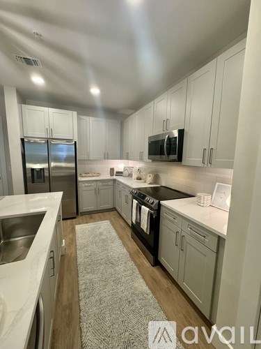 A kitchen with white cabinets and a grey rug on the floor.