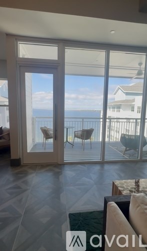 A living room with a view of the ocean through a sliding glass door.