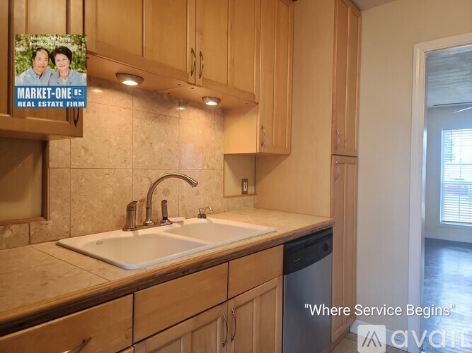 A room with a doorway leading to another room, a window with blinds, and a wooden floor.