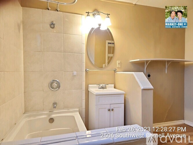 A bathroom with a tub, sink, and mirror.