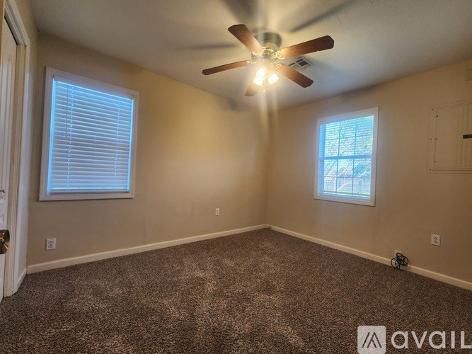 A room with a ceiling fan and two windows.