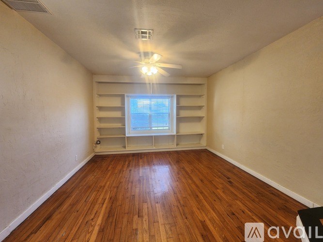 A room with wooden floors and a window with blinds.