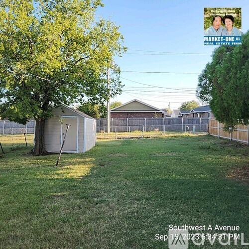 A backyard with a tree, a shed, and a fence.