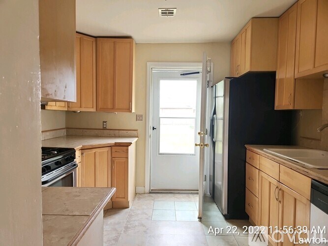 A kitchen with wooden cabinets and a black refrigerator.