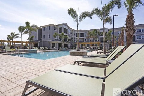 A pool area with sun loungers and a building in the background.