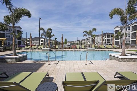 A pool surrounded by lounge chairs and palm trees.