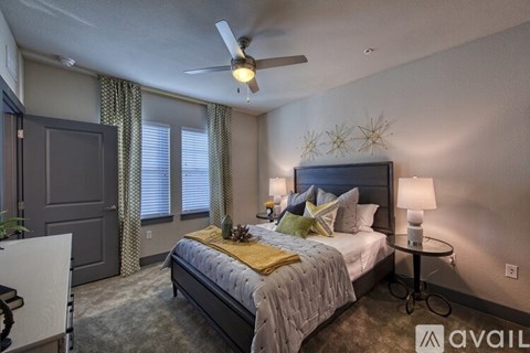 A bedroom with a bed, a ceiling fan, and a small table.