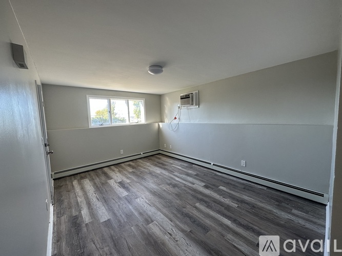 A room with a wooden floor and a window with blinds.
