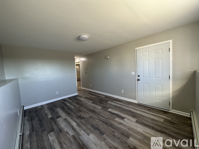 A room with a white door and wooden flooring.