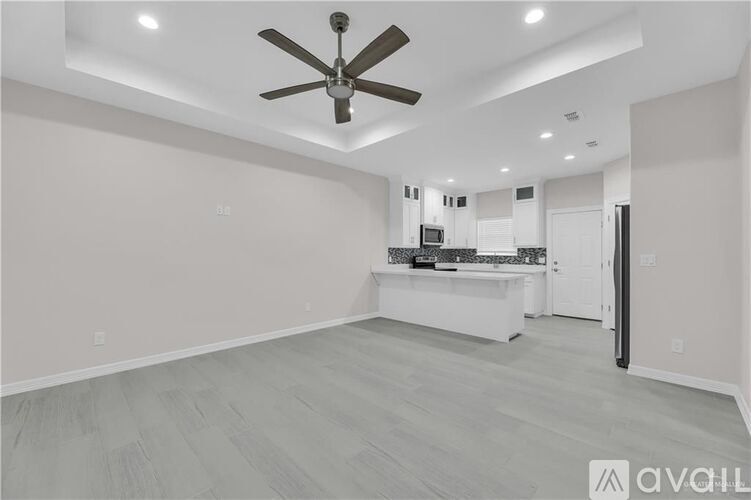 A spacious room with a ceiling fan and lighting fixtures.