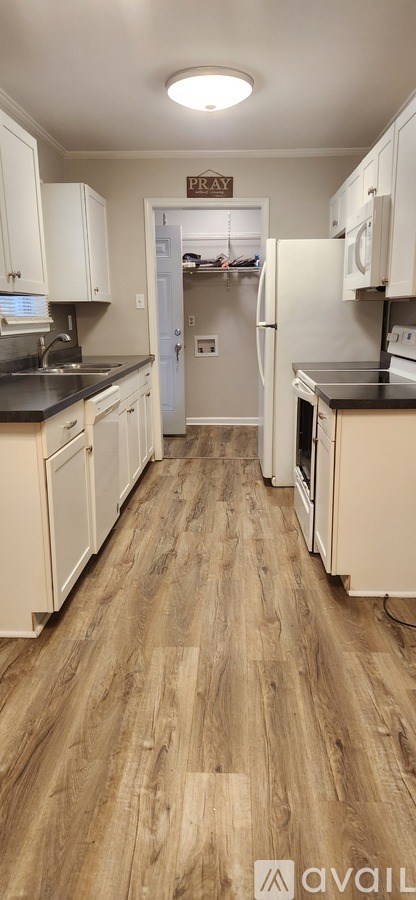 A kitchen with white cabinets and a wooden floor.