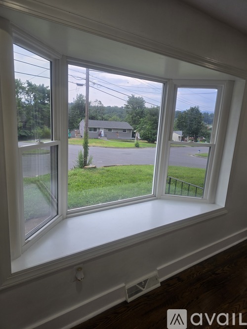 A window with a view of a green lawn and a house.