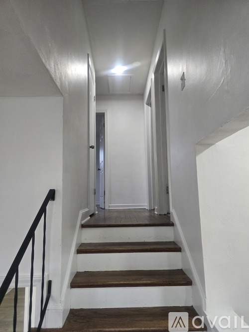 A staircase with a black railing and wooden steps leading to a door.