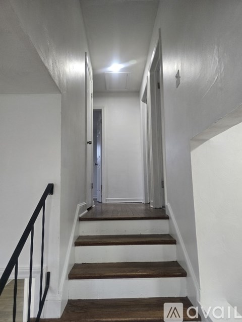 A staircase with a black railing and wooden steps leading to a door.