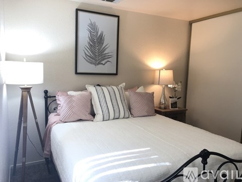 A bedroom with a white bed and a framed leaf picture on the wall.